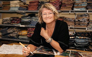 Tracy Krauter of Splash Fabrics sits at her design table creating fabric and looks at the camera.