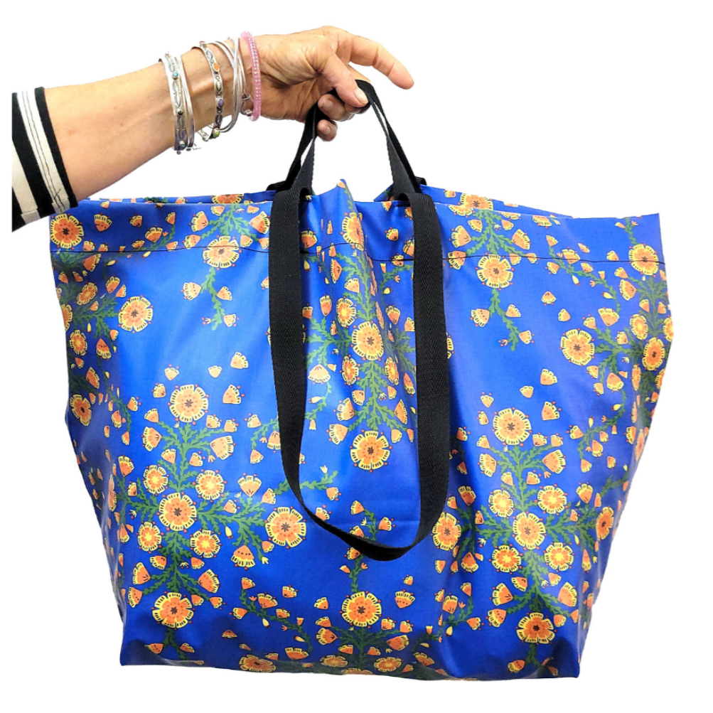 Blue floral-patterned tote bag held by a hand on a white background
