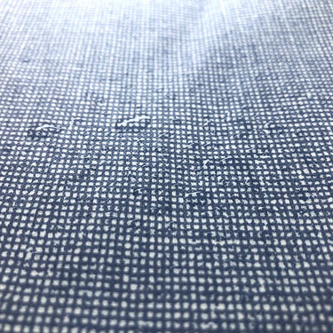 Water droplets on laminated cotton fabric in denim print. Blue laminated denim print.. Waterproof fabric.