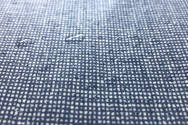 Water droplets on laminated cotton fabric in blue denim print. Waterproof fabric.