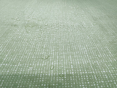 Water droplets on laminated light green fabric. Waterproof grass green fabric. 100% laminated cotton.